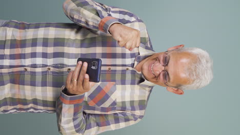 Vertical-video-of-The-man-looking-at-the-phone-is-happy.